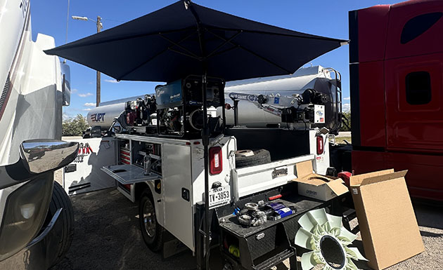 A white truck parked under a black umbrella, creating a striking contrast against the bright surroundings.