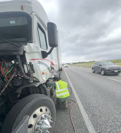 A man is diligently working on the front of a semi truck