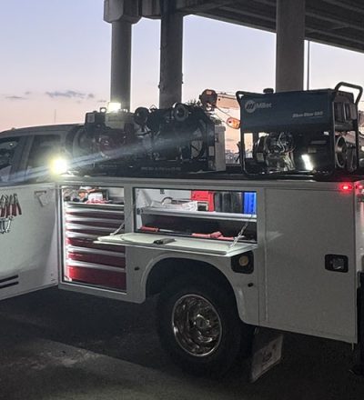 A nighttime scene of a truck with a ladder on its roof