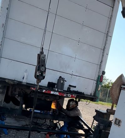 A crane lifts a large truck onto a flatbed