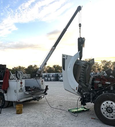 In a parking lot, a crane hoists a truck