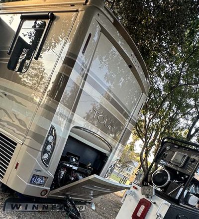 An RV parked in a lot alongside a truck and a trailer