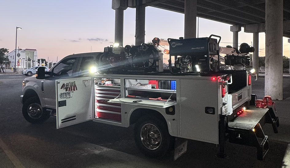 A nighttime scene of a truck with a ladder on its roof