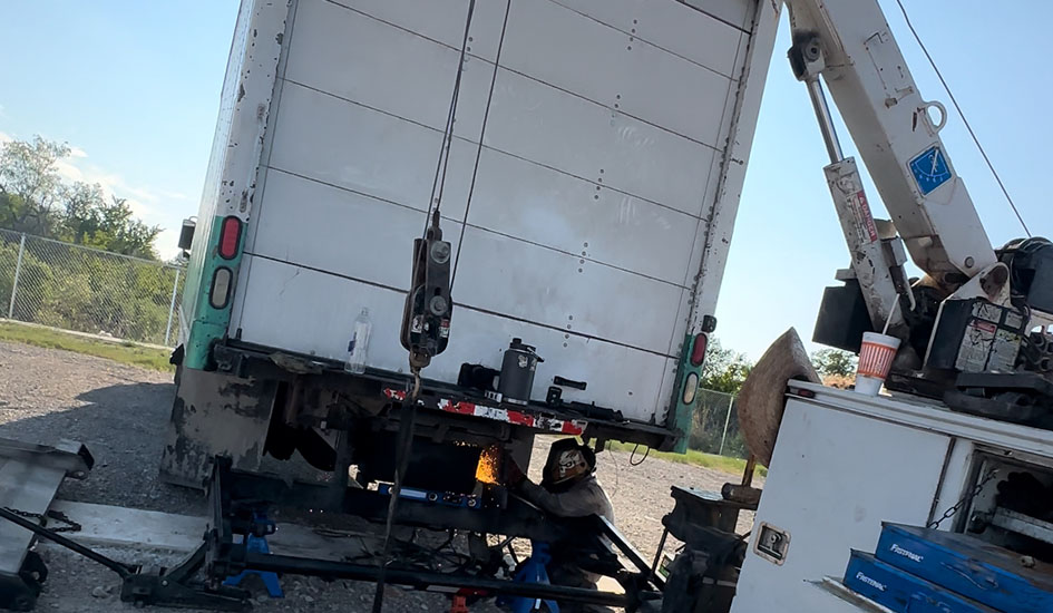 A crane lifts a large truck onto a flatbed