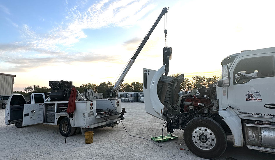 In a parking lot, a crane hoists a truck