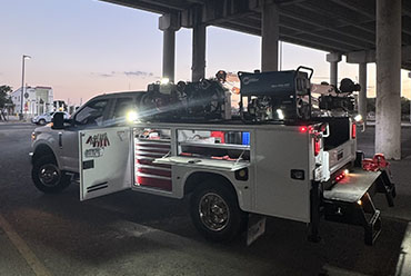 A nighttime scene of a truck with a ladder on its roof