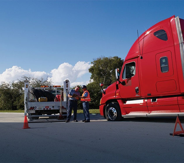 Two men stand beside a large semi truck